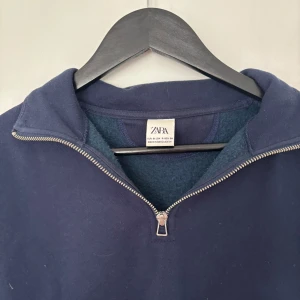 Marinblå half zip tröja från Zara - Snygg marinblå långärmad tröja från Zara med half zip-dragkedja och hög krage. Perfekt för lager-på-lager och chill dagar. Mjuk insida och klassisk passform gör den både bekväm och stilren.