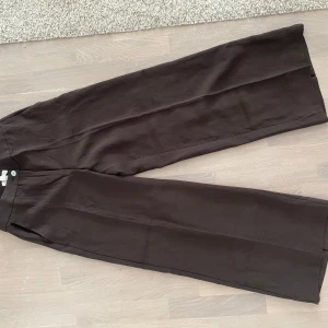 Bruna vida linnebyxor från H&M - Snygga bruna linnebyxor från H&M i storlek 38. Vida ben och hög midja ger en chill och trendig look. Byxorna har en enkel design med knappstängning och är tillverkade i ett lätt och luftigt linnematerial.