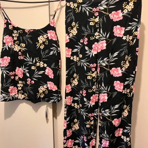Nytt set byxor och linne strl M - Blommigt set med vida byxor och linne i strl M från Vero Moda. Kollektion: Vmsimply easy  Byxorna har resår i midja. Linnet har justerbara axelband. Material: viskos  Helt nytt, aldrig använt.  