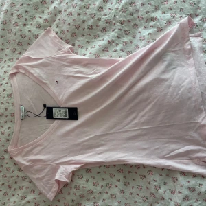 Ljusrosa t-shirt från Tommy Hilfiger - Supersöt ljusrosa t-shirt från Tommy Hilfiger med klassisk v-ringning och liten broderad logga på bröstet. Står XS, kan även passa S. Nypris 400kr, köpt för 280kr (se prislapp)