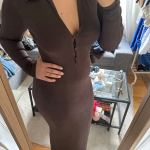 Brun långklänning från NA-KD - Snygg brun långklänning med lång ärm och djup v-ringning framtill. Väldigt bra skick. 