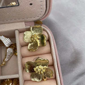Guldiga blommiga örhängen - Stora statement-örhängen i form av blommor i guldig metall. De har detaljerade kronblad och en glansig finish som verkligen drar blickarna till sig. Perfekta för dig som vill sticka ut och addera en cool touch till din stil.