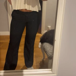 Mörkblå kostymbyxor  - Snygga mörkblå kostymbyxor med tunna vita ränder. Byxorna har rak passform och låg midja 💙🤍använda fåtal gånger men nere vid ena foten har sömnen sprättats upp. (Se bild 4) men väldigt lätt att antingen vika upp (som på bild 5) ,sy till igen eller om man skulle vilja sprätta upp andra sidan för att få de längre 🤍