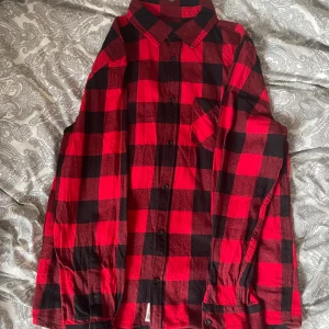 Röd och svart rutig skjorta - Snygg röd och svart rutig skjorta med klassisk krage och knäppning framtill. Skjortan har långa ärmar och en bröstficka. Perfekt för dig som gillar en avslappnad men ändå trendig stil. Säljer mycket skjortor så köp gärna flera i ett bundle!