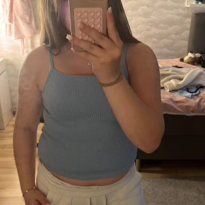 Ljusblå ribbad linnetopp från H&M - Supersöt ljusblå ribbad linnetopp från H&M med smala axelband och croppad passform. Perfekt för varma dagar och enkel att matcha med både jeans och kjol. Mjuk och stretchig, sitter snyggt och bekvämt.