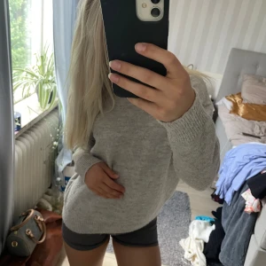 Ljusgrå stickad tröja från Gina tricot - Mysig ljusgrå stickad tröja med rund hals och långa ärmar. Perfekt och enkel att matcha med både jeans och kjol. Tröjan har en klassisk passform och ribbade muddar vid ärmslut och nederkant. Den kommer från Gina tricot och är i storlek XS.