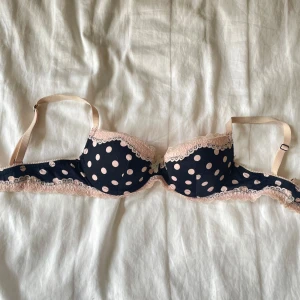 Två söta spets-bh:ar i rosa och prickigt - Säljer två bh:ar: en mörkblå med ljusrosa prickar, spetskant och rosett, samt en puderrosa trekants-bh med spetsdetaljer och justerbara axelband. 200 för den prickiga och 100 för den mörk rosa ❤️Båda är mjuka och bekväma, perfekta under en tunn topp eller skjorta. Super söta bh som knappt blivit använda!!❤️