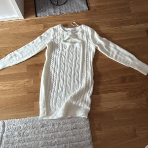 Vit stickad tröja från Rainbow - Säljer en stilren vit stickad tröjkläning från Rainbow med ett klassiskt flätmönster. Tröjaklänningen har långa ärmar och en rund halsringning, perfekt för kyligare dagar.🧶✨