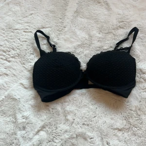 Svart spets-bh från Auden - Säljer en elegant svart bh från Auden med spetsdetaljer. Bh:n har justerbara axelband och en klassisk hakknäppning bak. Perfekt för en stilren look.