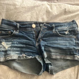 Jeansshorts från Hollister - Säljer ett par snygga jeansshorts från Hollister. De är lågmidjade med slitna detaljer, finns liten färgfläck vid gylfen men den synns ej! Skulle säga att dom passar xs/s