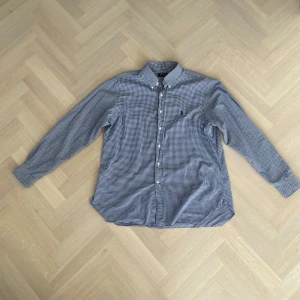 Blårutig skjorta från Ralph Lauren - Säljer en klassisk blårutig skjorta från Ralph Lauren. Skjortan har långa ärmar och knappar framtill. Storlek 17 1/2 skulle säga typ L/XL. Den är broderad med en liten logotyp på bröstet. Perfekt för en stilren look på kontoret eller skolan! 