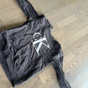 Svart tröja från Calvin Klein Jeans - Säljer en svart tröja från Calvin Klein Jeans med deras ikoniska logga i vitt på framsidan. Tröjan har långa ärmar och en rund halsringning. Perfekt för en stilren och avslappnad look.