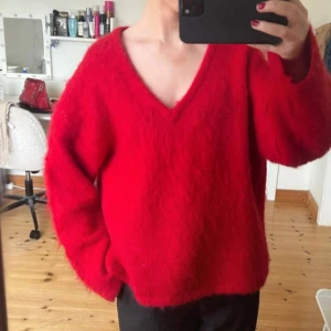 Röd fluffig tröja med v-ringning - Säljer en supermjuk och fluffig röd tröja med v-ringning. Perfekt för att hålla sig varm och stilren under kyligare dagar. Tröjan har en lös passform och långa ärmar, vilket gör den både bekväm och trendig. Den är från H&Ms exklusiva sortiment och köptes för 699 