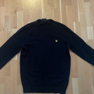 Svart tröja från Lyle & Scott - Säljer en stilren svart tröja från Lyle & Scott med deras ikoniska logga på bröstet. Tröjan är använd 1 gång men var för liten så helt nytt skick. Skick 10-10. Nypris 650 kr. Storlek L men passar också M.