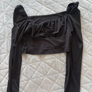 Svart långärmad topp - Snygg svart långärmad topp med rynkade detaljer och en unik design. Perfekt för en trendig look.🖤