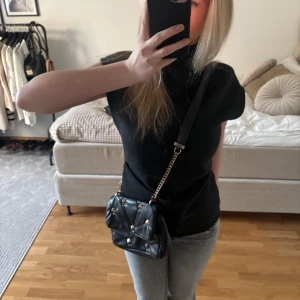 Svart quiltad axelväska med nitar - Snygg svart axelväska med quiltad design och nitar. Gammal modell från Zara. Själva väskan är i bra skick men den har små rost defekter på bandet men ingenting man tänker på.💞