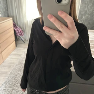 Svart långärmad skjorta - Snygg svart långärmad skjorta med knappar framtill. Perfekt för en stilren look. Passar bra till både jeans och kjol.