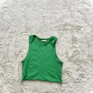 Grön ribbad linnetopp  - Säljer en snygg grön ribbad linnetopp. Perfekt för varma dagar med sin ärmlösa design och sköna passform. Toppen är enkel att matcha med olika outfits och ger en fräsch look.