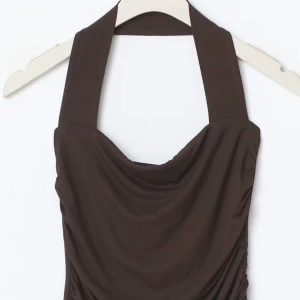  topp från Gina tricot - Helt oanvänd  brun halterneck topp med draperad design.  Toppen har en åtsittande passform och är tillverkad i ett mjukt material. Har kvar ettiket