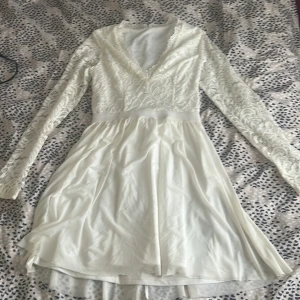 Vit spetsklänning med lång ärm - Elegant vit klänning med v-ringad spetsöverdel och långa ärmar. Storlek 34 från NLY Trend. Använd en gång. Jättefint skick! Passar mig som har storlek S då den är lite stretchig. 