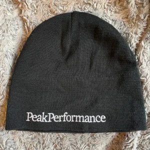  Peak Performance mössa - Snygg svart mössa från Peak Performance med broderad logga framtill. Perfekt för kyliga dagar och stilren look.