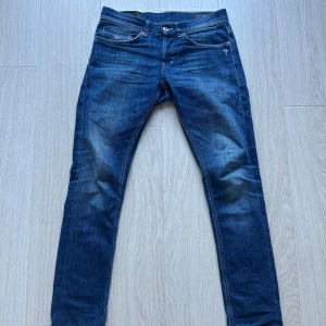 Mörkblå jeans från Dondup - Snygga mörkblå jeans från Dondup med en klassisk femficksdesign. De har en knappgylf och subtila slitningar för en trendig look. Perfekta för en stilren vardagsoutfit. Dom är i storlek 30 och sparsamt använda.