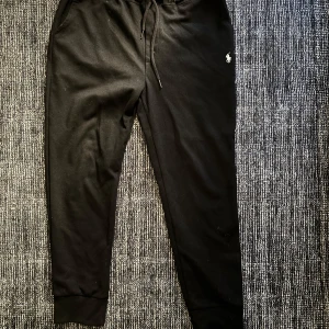 Svarta mjukisbyxor från Polo Ralph Lauren - Snygga svarta mjukisbyxor från Polo Ralph Lauren med dragsko i midjan och ribbade muddar vid bensluten. 