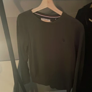 Mörkgrön tröja från U.S. Polo Assn. - Säljer en stilren mörkgrön tröja från U.S. Polo Assn. med rund hals och långa ärmar. Perfekt för en avslappnad och klassisk look.