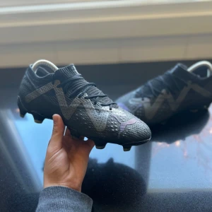 Svarta fotbollsskor med snörning - Snygga svarta fotbollsskor med snörning och en modern design. Skorna har en mönstrad yta och dobbar för bra grepp på planen. Perfekta för fotbollsträning och matcher. Priset kan absolut diskuteras. Kontakta för mer information!