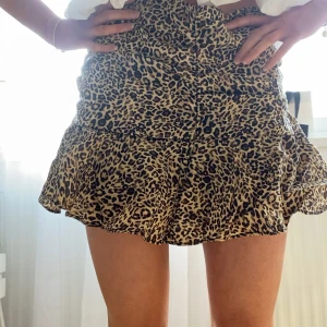 Leopardmönstrad kjol från Zara - Snygg leopardmönstrad kortkjol med volangdetaljer. Perfekt för att ge en trendig touch till din outfit. Kjolen har en bekväm passform och är lätt att matcha med olika toppar. Så snygg till sommaren! Storlek S men passar även en XS🐆 endast använd en enstaka gång!!!
