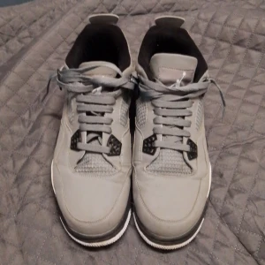 Grå Nike Air Jordans - Snygga grå Nike Air Jordans med klassisk design och snörning. Skorna har en vit sula med synlig luftdämpning och svarta detaljer. Perfekta för en stilren look.