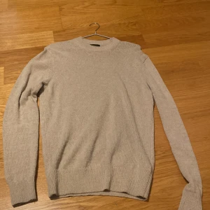 Massimo Dutti beige stickad tröja – litet hål under armen - Beige tunn stickad tröja från Massimo Dutti med rund hals och klassisk passform. Mjuk och stilren – perfekt till vardags eller som lagerplagg. Obs: mindre hål under ena armen (enkelt att sy ihop). Storlek: M Skick: Bra, förutom hålet Nypris: 800kr Mitt pris: 100