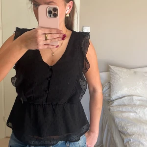 Svart ärmlös blus med knappar - Super fin svart blus med v-ringning och knappar framtill från about you💕