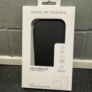 Svart plånboksskal från Ideal of Sweden - Säljer ett stilrent svart plånboksskal från Ideal of Sweden, för iPhone 12/12 Pro. Perfekt för att skydda din telefon med stil. Plånboken har en elegant design. 