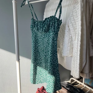 Grön blommig klänning - Söt grön klänning med vita blommor och smala axelband som knyts. Perfekt för sommarens varma dagar. Kontakta för fler bilder💞💞