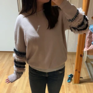 rosa tröja - Säljer en rosa tröja med unika randiga detaljer på ärmarna i svart, vit och grå. Tröjan har en normal passform och långa ärmar. Perfekt för att ge din outfit en trendig touch!