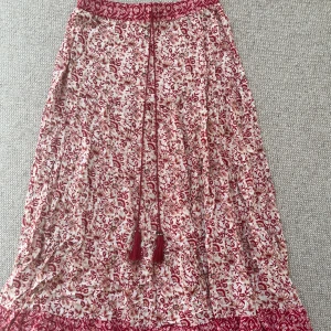 Blommig långkjol från Zara - Säljer en vacker blommig långkjol från Zara i rött och vitt. Kjolen har ett fint knytband i midjan och är perfekt för sommarens varma dagar.😊