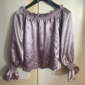 Ljuslila supersöt blus - Säljer en ljuslila offshoulder blus med långa ärmar i glansigt och fint material💜Från BikBok i storlek S och i bra skick. Passar både till vardags/skola och vid fest eller uppklädda tillfällen. Bara att skriva om ni har frågor eller vill ha fler bilder🥰