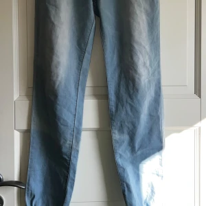 Ljusblå jeansbyxor med snörning - Snygga ljusblå jeansbyxor med elastisk midja och vit snörning. Perfekta för en avslappnad stil. Byxorna har en rak passform och är tillverkade i ett bekvämt material.