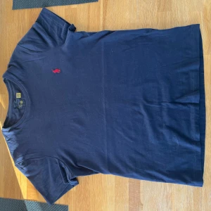 Mörkblå t-shirt från Ralph Lauren - Säljer en stilren mörkblå t-shirt från Ralph Lauren, passform slimfit. Använd två gånger, säljer då jag sparat den för sommaren men växte lite för snabbt