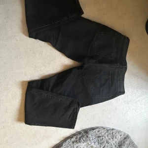 Svarta jeansbyxor - Snygga svarta jeansbyxor med en klassisk femficksdesign. Byxorna har en rak passform och är perfekta för en stilren look. De är tillverkade i ett slitstarkt material och har en knappgylf framtill.(seatle) köparen står för frakten 