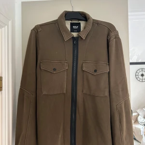 Mörkgrön overshirt från Replay - Säljer en knappt använd snygg mörkgrön jacka från Replay. Jackan har en dragkedja framtill och två bröstfickor med knappar. Väldigt skönt material inuti. Passar mindre L och M