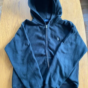 Ralph Lauren Zip Hoodie - Säljer min ralph lauren zip hoodie i fint skick. Storleken är M men jag skulle säga att den passar en person som brukar ha storlek S. Färgen är svart