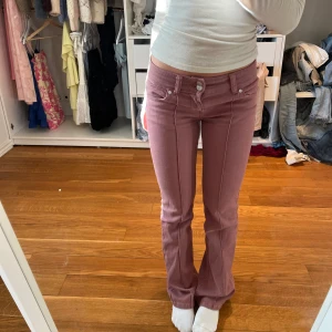Rosa lågmidjade jeans  - Snygga rosa bootcut byxor med hög midja och klassisk femficksdesign. Byxorna har en dragkedja och knapp framtill. Perfekta för en trendig look. Bara använt 2 gånger