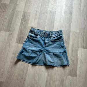 Jeanskjol från LAB Industries - Säljer en blå jeanskjol från LAB Industries med retro/regular fit. Kjolen har klassiska fickor fram och bak samt rå kant nertill för en avslappnad look. Perfekt för dig som gillar denim och vill ha en enkel men snygg kjol i garderoben.