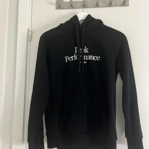 Svart hoodie från Peak Performance - Säljer en svart hoodie från Peak Performance med vit logga på bröstet, passar till kvinna som man! Aldrig använt. 