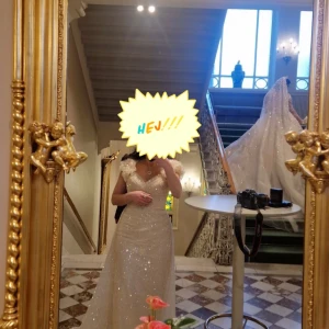 Glittrig champagnefärgad långklänning med puffärmar - Säljer en elegant långklänning i champagnefärg med glittrigt tyg och v-ringad omlottliv. Klänningen har korta puffärmar och markerad midja, vilket ger en romantisk och lyxig känsla. Perfekt för bal eller fest. Vid snabb köp kan priset diskuteras 