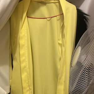 Ljusgul kavaj från Chi Zu Collection - Säljer en ljusgul kavaj från Chi Zu Collection i storlek 38. Kavajen har en klassisk passform med långa ärmar och är tillverkad i ett slätt, lätt material. Perfekt för att addera färg till din outfit.