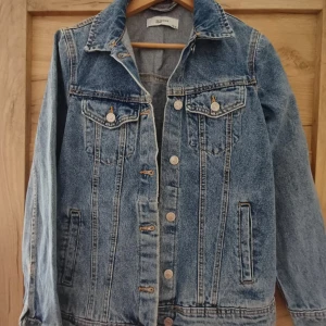 Blå jeansjacka -  Blå jeansjacka med knappar framtill och två bröstfickor med lock. Jackan har lång ärm och perfekt nu till sommaren när man vill ha mer lätta jackor!