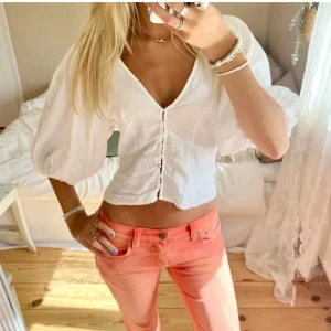 Vit blus med puffärmar och knappar - Säljer en söt vit blus med v-ringning och puffiga trekvartsärmar. Blusen har knappar framtill och är lätt croppad, perfekt till både jeans och kjol. Enkel och fräsch stil som passar till många tillfällen. Aldrig använd av mig men köpt på plick💕 som ny skick 